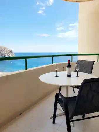views from the balcony to the see with a table with two glasses and a bottle of wine